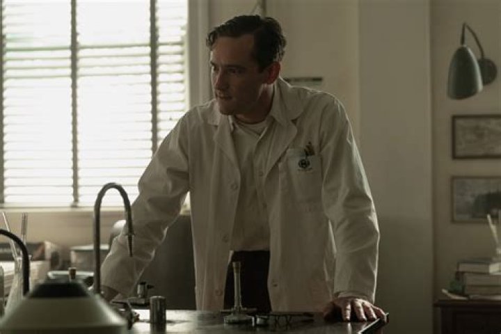 Calvin (Lewis Pullman) rests his chin on Elizabeth's (Brie Larson) hand as she stares him affectionately in 'Lessons in Chemistry'